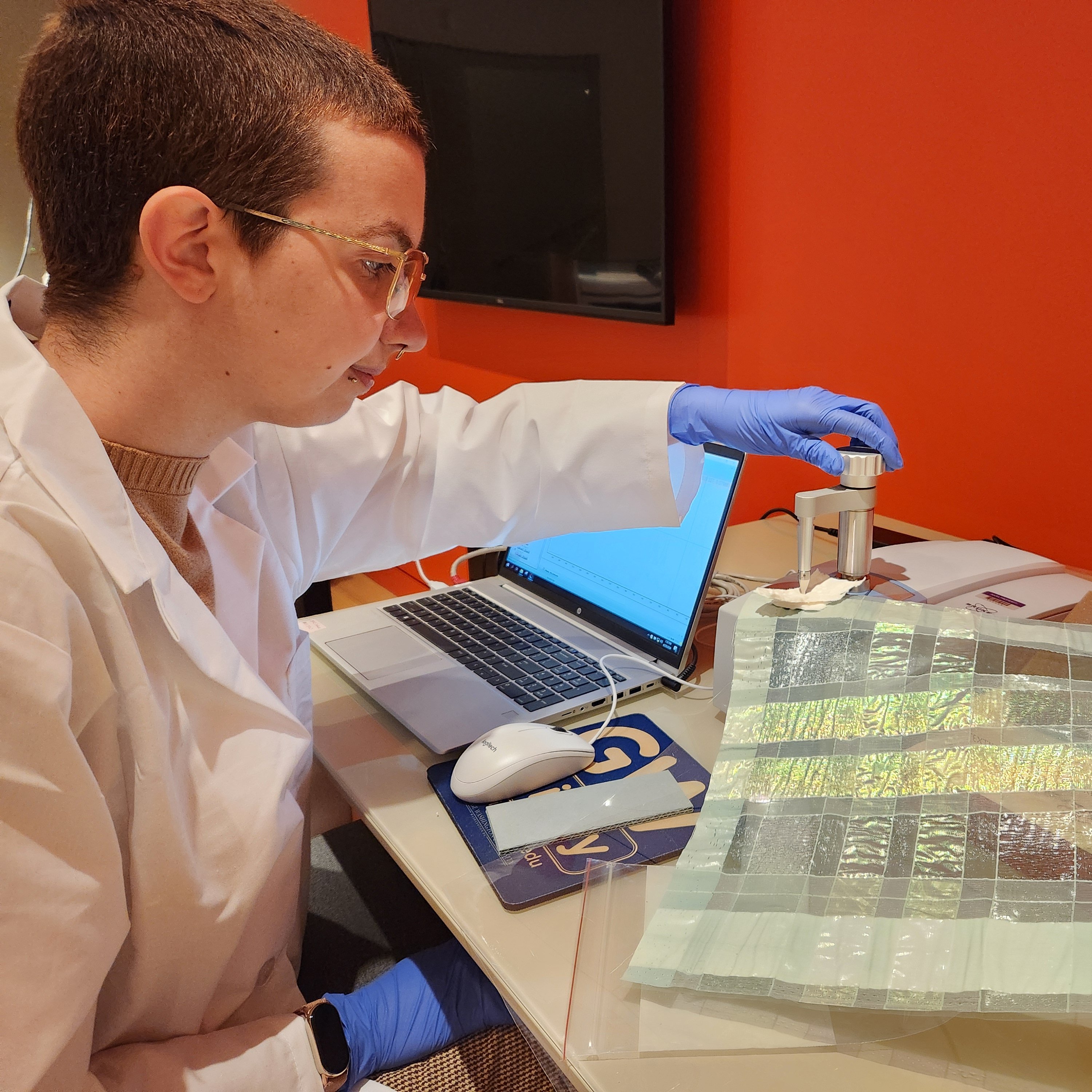 A picture of Laís doing FTIR-ATR analysis of a bright green textile fragment.