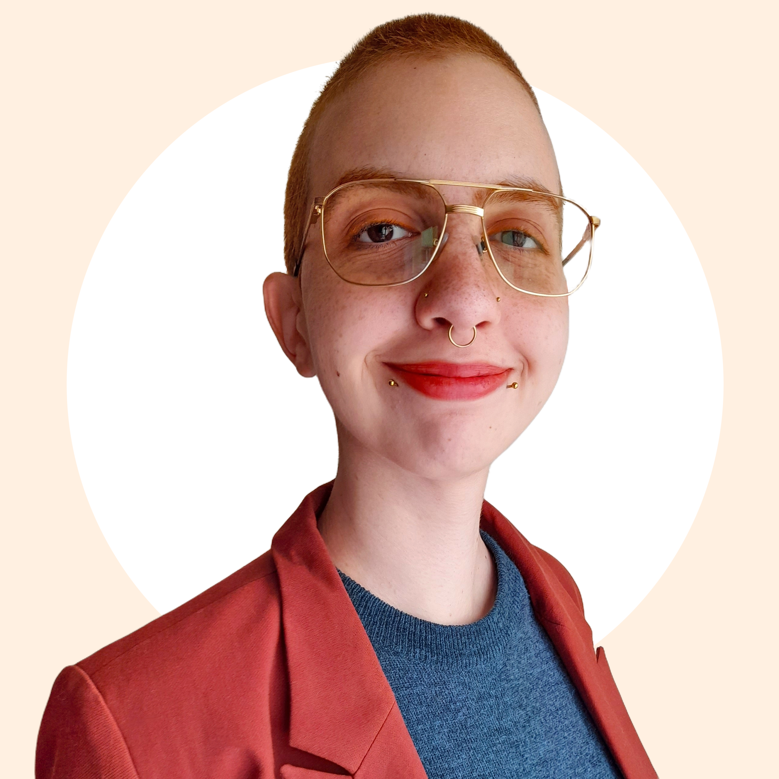 Avatar de Laís. Laís é uma pessoa branca, com cabelo ruivo bem curto e olhos castanhos. Usa um óculos dourado tipo aviador e piercings delicados no septo, nas abas do nariz e no lábio inferior. Está vestindo um suéter azul sobreposto por um blazer cor telha.